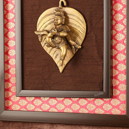 Brass Baby Krishna Baal Gopal Resting on a Leaf Hanging on Wooden Frame with Premium Fabric - 13" x 14"