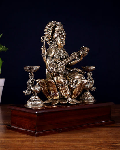 Brass Superfine Goddess Saraswati Idol with Twin Peacock Lamps on Wooden Base – 9.5 Inch
