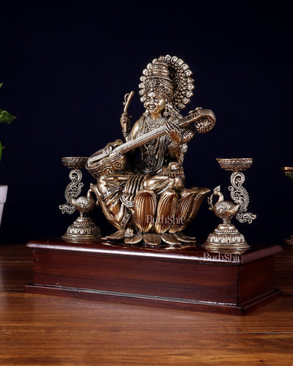 Brass Superfine Goddess Saraswati Idol with Twin Peacock Lamps on Wooden Base – 9.5 Inch - Budhshiv.com